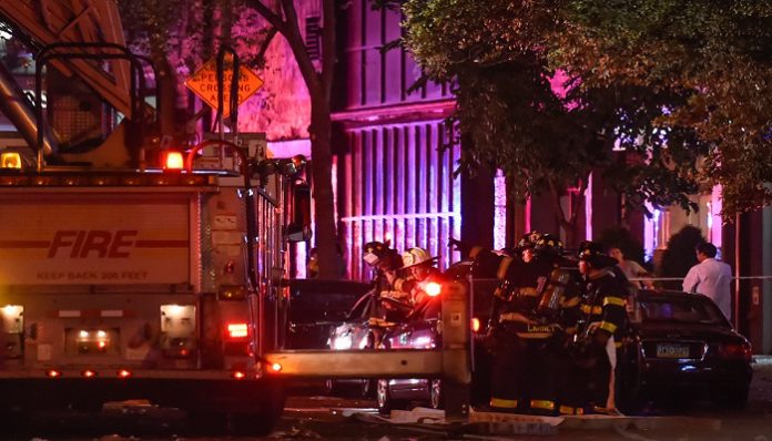 New York City firefighters stand near the site of an explosion in the Chelsea neighborhood of Manhattan, New York