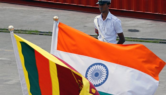A Navy officer stands in front of India's and Sri Lanka's national flags as Indian Coast Guard Ship Shoor is in the Colombo port during its visit in Colombo